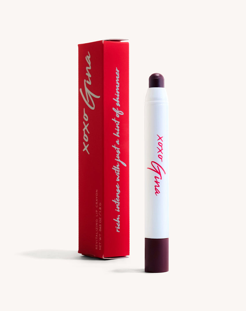An upright lipstick with a dark burgundy color. Behind the lipstick is the matching red box. 